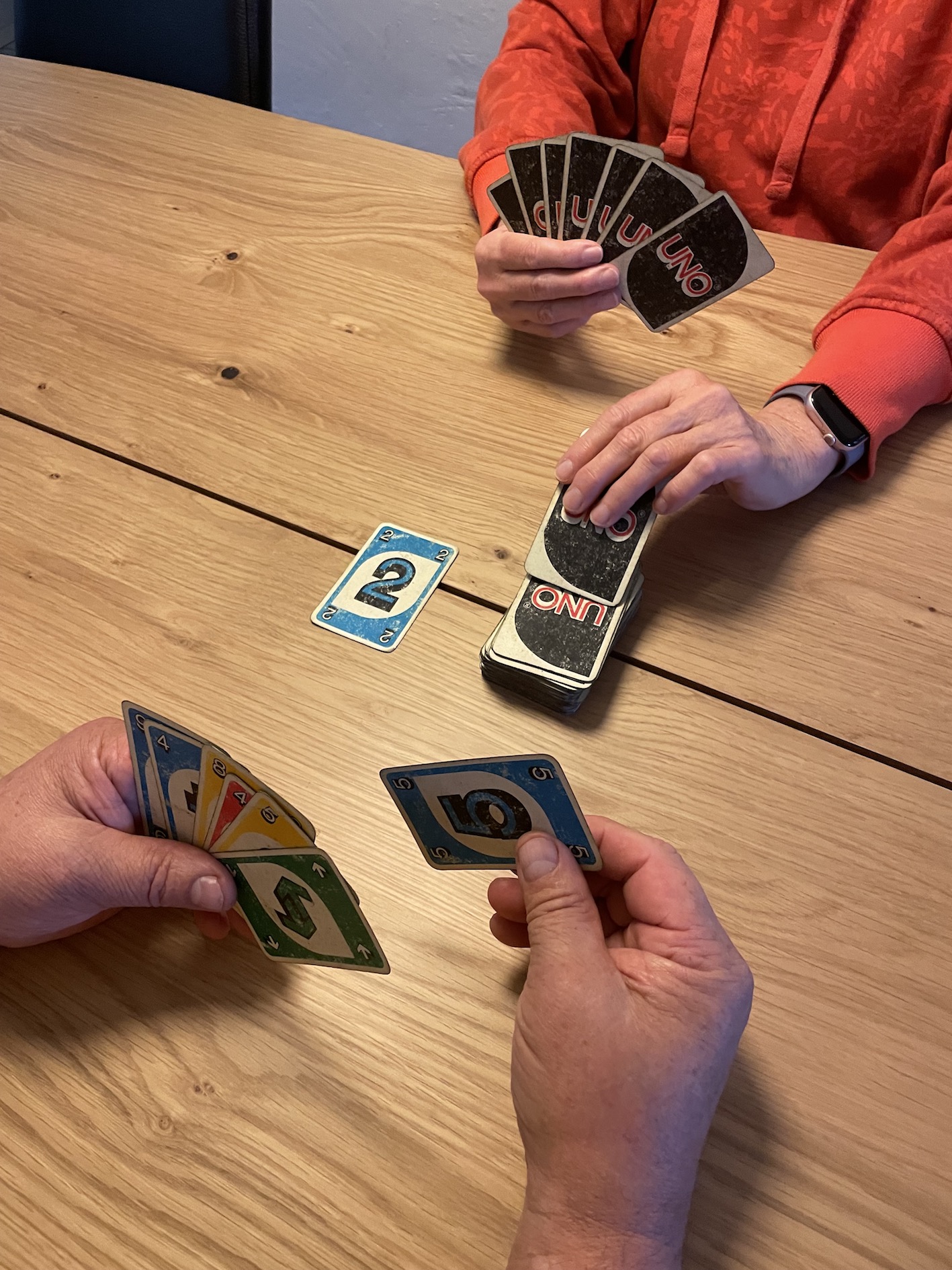 kuvassa näkyy kahden henkilön kädet pelaamassa Uno-korttipeliä